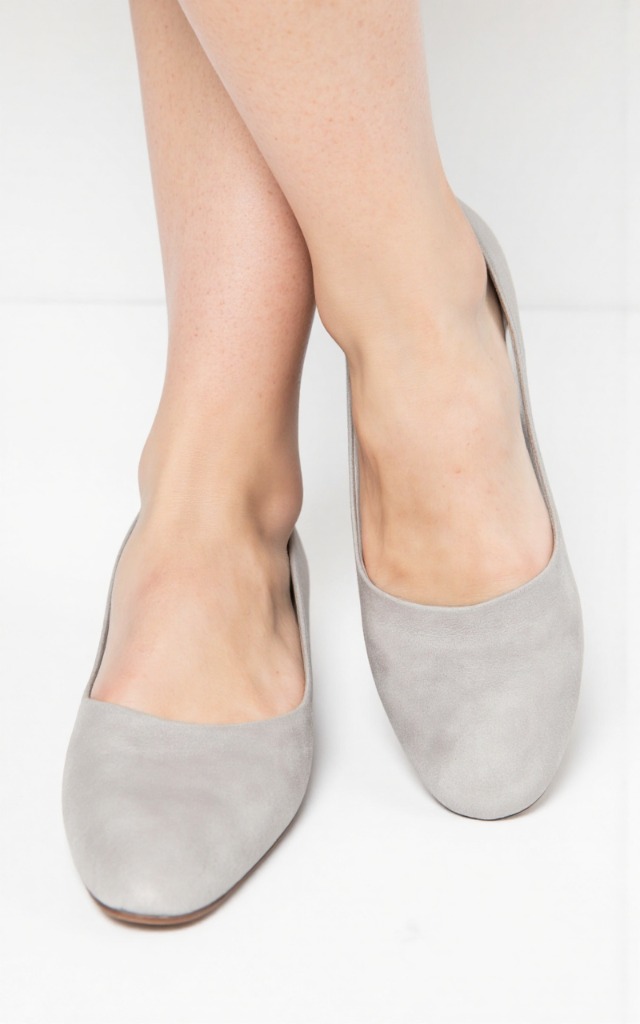A female model wearing round   toe shoes, against a white background, with a close   up of the feet